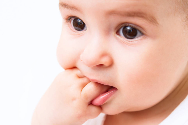 Mooie baby portret met hand in mond op witte achtergrond - Foto, afbeelding