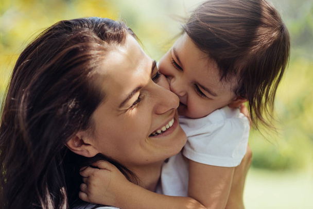 Beautiful portrait of happy smiling mother and her little cute daughter have fun outdoors. Good relationship of happy family. Happy Mother's Day. Motherhood and childhood concept. - Photo, image
