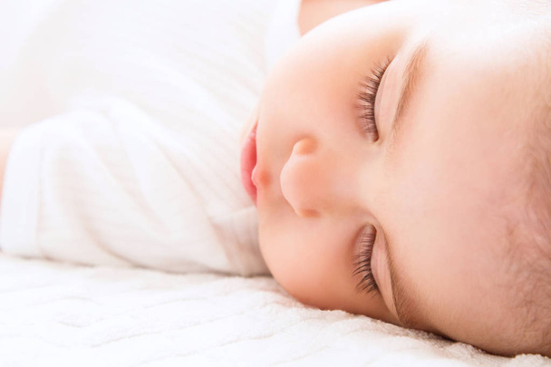Close-up portrait of a beautiful sleeping baby on white bakcground - Valokuva, kuva