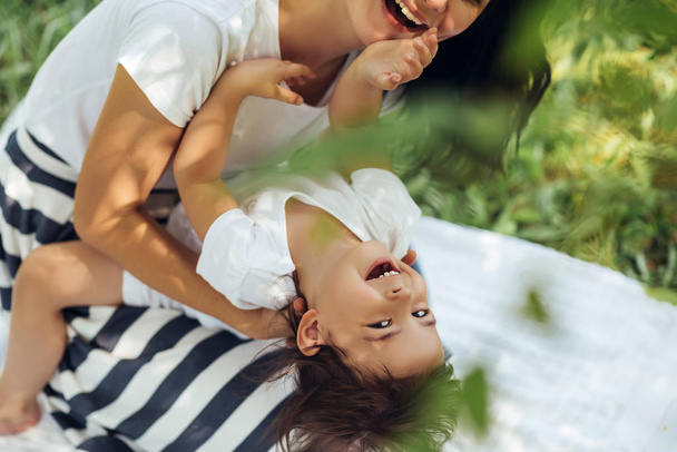 Adorable above view portrait of happy smiling little cute daughter kid have fun with mother outdoors in the park. Good relationship of mom and child. Happy Mother's Day. Happy childhood concept. - Fotó, kép