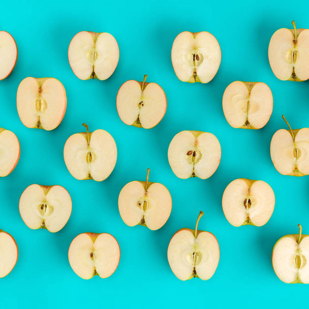 Fruit pattern on blue background. Apple halves geometrical layout. Flat lay, top view. Food background. - 写真・画像