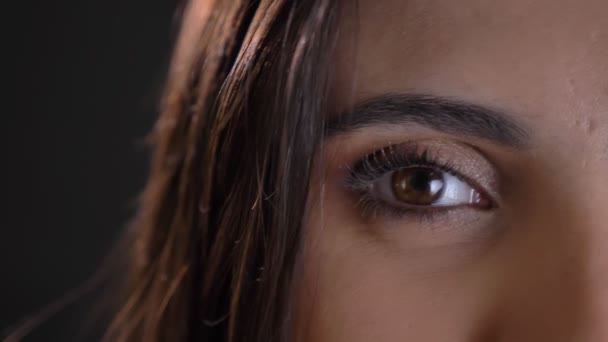 Nahaufnahme-Augenporträt eines kaukasischen langhaarigen brünetten Mädchens, das lächelnd in die Kamera auf schwarzem Hintergrund schaut. - Filmmaterial, Video