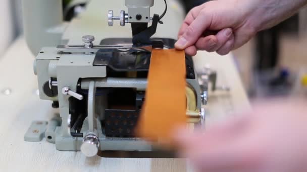 Operator is adjusting automatic leather skiving machine in a haberdashery manufactory. Splitting, aligning and cutting edge of leather details, electrical motor-driven machine - Footage, Video