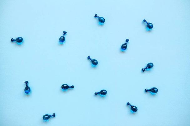 Charges ou capsules avec de l'acide hyaluronique sur fond bleu. Soins de la peau et santé du visage
 - Photo, image