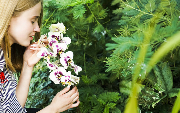 Young beautiful woman smelling purple  orchid flowers - Foto, afbeelding