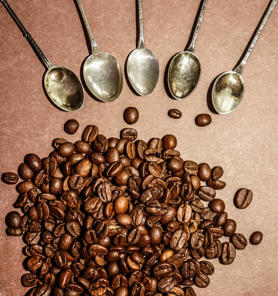many vintage spoons around coffee beans. isolated on brown background  - Zdjęcie, obraz