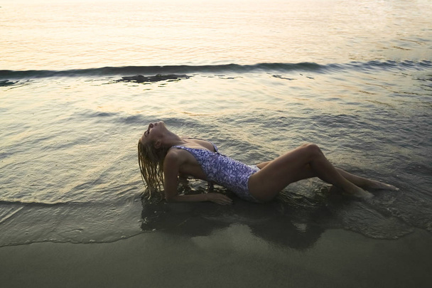 Attractive slim woman resting on the beach lying down.  - Fotó, kép