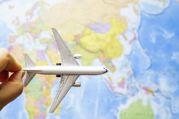 male hand holding airplane toy above  map background. - Foto, Imagen