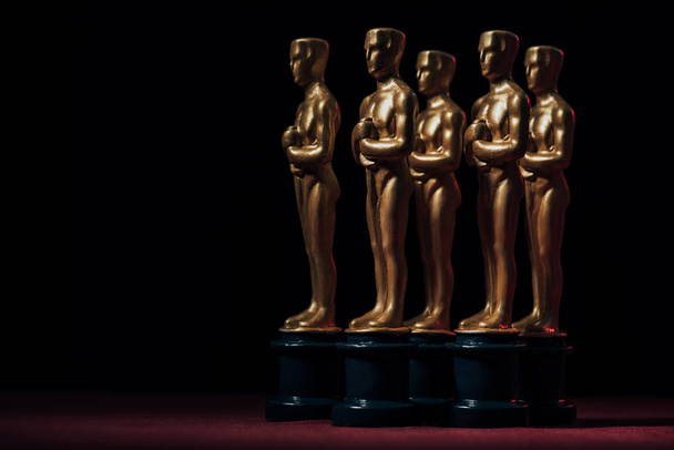 KYIV, UKRAINE - JANUARY 10, 2019: row of golden oscar award statuettes on black background with copy space - Foto, imagen