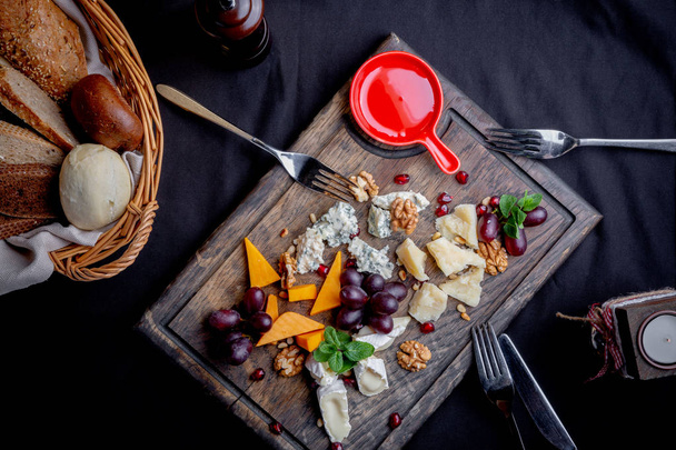 Cheese plate served with grapes, honey and nuts on a wooden background. Various types of cheese - Foto, Imagen
