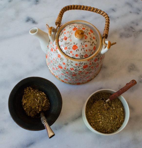 A yerba mate infusion with a withe marble background. A wooden gourd and the metal straw. - Photo, Image