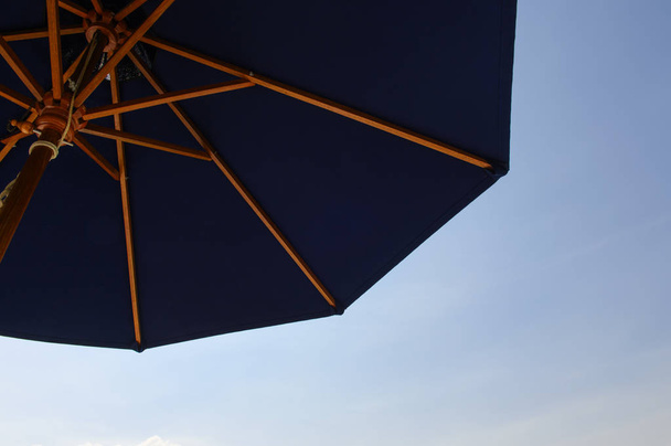 Patrząc na błękitne niebo pod niebieski parasol - Zdjęcie, obraz