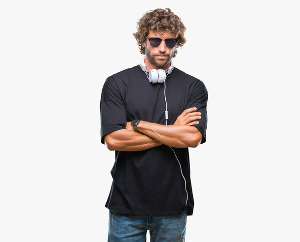Jóképű Spanyol férfi zenehallgatás fejhallgató viselése elszigetelt háttér szkeptikus, és ideges, rosszalló kifejezés arcán keresztezett karokkal. Negatív személy. - Fotó, kép