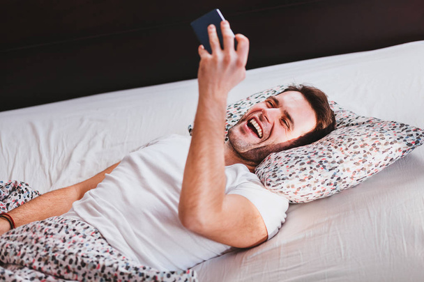 Young man taking a selfie in the bed - Foto, imagen