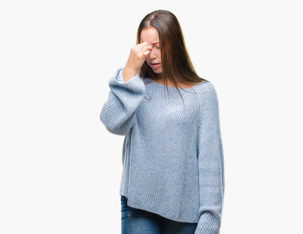 若い美しい白人女性の孤立した背景疲れて摩擦鼻と目の疲労や頭痛を感じて冬セーターを着ています。ストレスと欲求不満のコンセプト. - 写真・画像