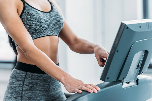 cropped shot of african american girl in sportswear training on treadmill in gym - Zdjęcie, obraz