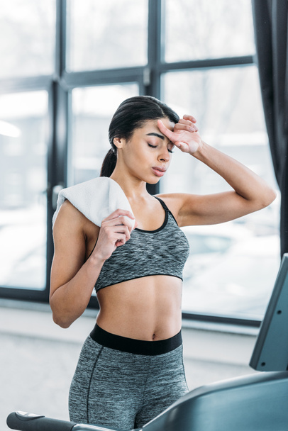 tired african american sportswoman holding towel while working out in gym - Photo, Image