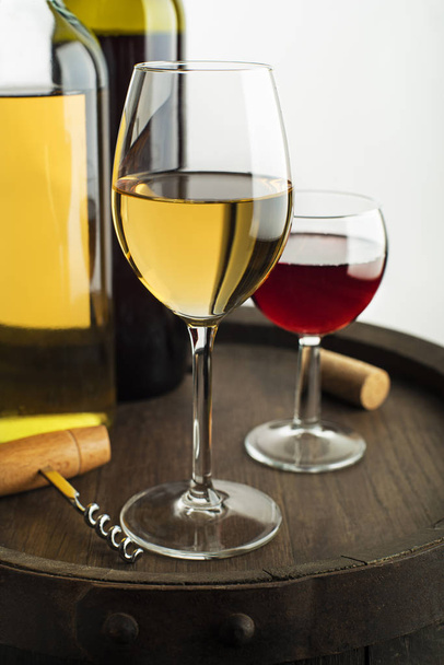 Glass and bottle of red wine and white wine on wooden barrel - Fotó, kép