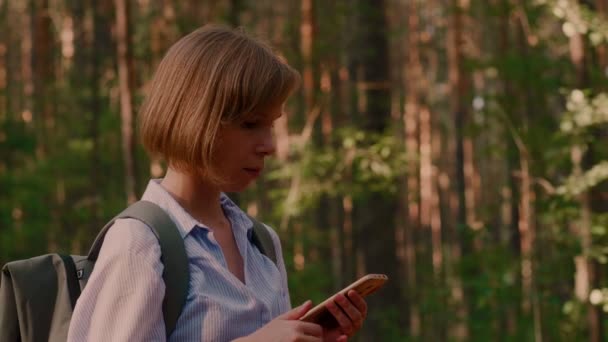 Потерянный турист молодая женщина делает звонок с помощью смартфона в окружении летнего леса
 - Кадры, видео