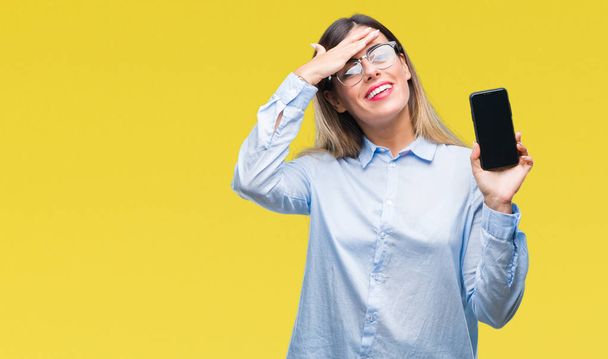Young beautiful business woman showing blank screen of smartphone over isolated background stressed with hand on head, shocked with shame and surprise face, angry and frustrated. Fear and upset for mistake. - Photo, Image
