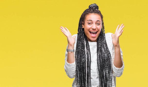 Jeune fille afro-américaine cheveux tressés portant un pull sur fond isolé célébrant fou et étonné pour le succès avec les bras levés et les yeux ouverts hurlant excités. Concept gagnant
 - Photo, image