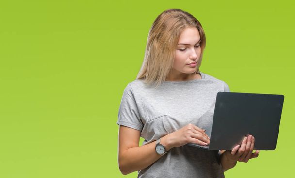 Young caucasian woman using computer laptop over isolated background with a confident expression on smart face thinking serious - Φωτογραφία, εικόνα