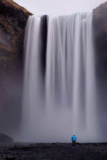 Longa exposição da pessoa olhando para a cachoeira Skogafoss na Islândia - Foto, Imagem
