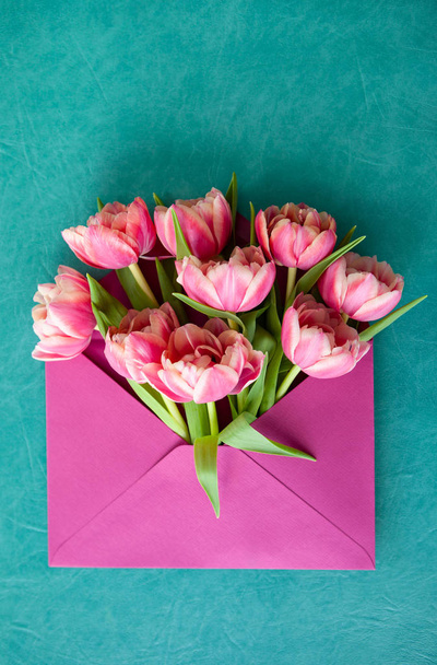 Pink envelope with fresh spring flowers on blue  background - Фото, зображення
