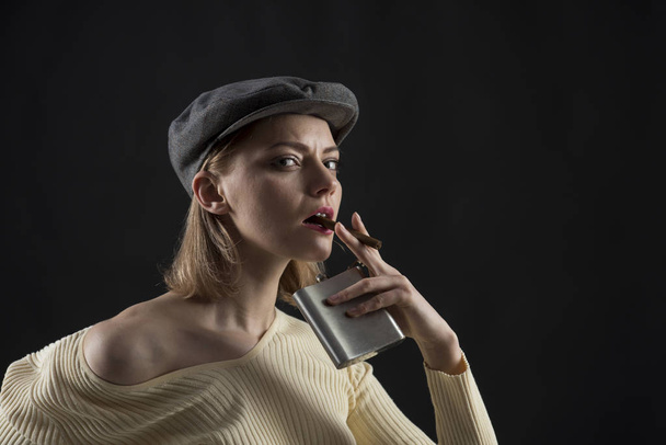 Puff away at a cigar. Sensual woman hold hip flask smoking cigar. Pretty smoker with alcohol container. Addicted woman with sexy look. Unhealthy lifestyle and bad habit. Alcohol and tobacco addiction - Photo, Image