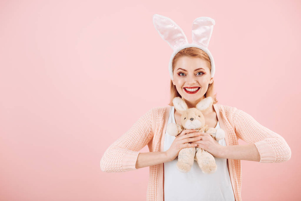 happy woman in bunny ears with toy. Woman in rabbit bunny ears. Happy easter. Spring holiday. Girl with hare toy. Egg hunt. Easter eggs as traditional food. copy space. Feeling joy about holiday - Fotografie, Obrázek