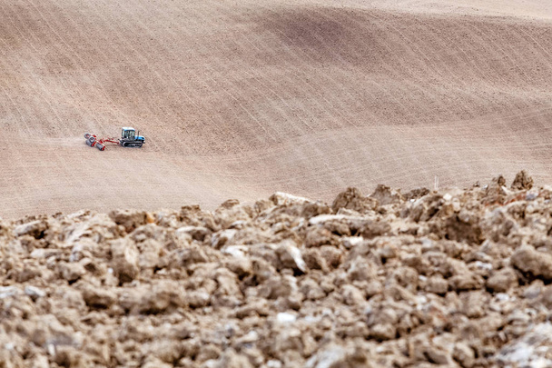 Tracteur avec une charrue ou un cultivateur travaillant sur un sol désertique sec
 - Photo, image