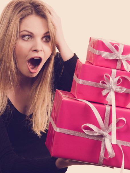 Celebration and giving concept. Blonde young woman with pink gift boxes in hands. Girl looking surprised. - Foto, Bild