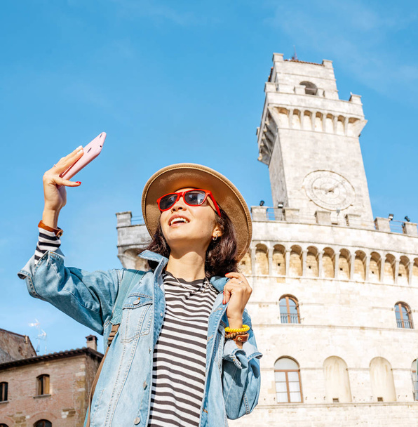 Happy asian tourist woman with smartphone in old town of Montepulciano, Tuscany. Vacation and travel in Italy concept - Photo, Image