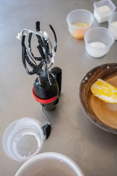 Used and dirty manual whisk stirrer with whipped cream for homemade butter. - Photo, Image