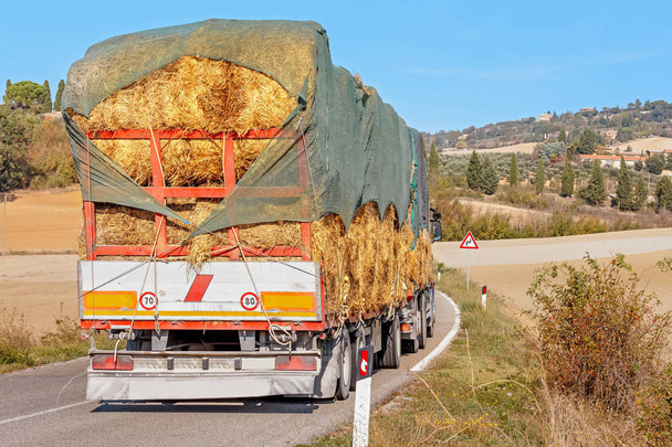 Raskas kuorma-auto, jossa heinää on maaseudulla Toscanan tiellä
 - Valokuva, kuva