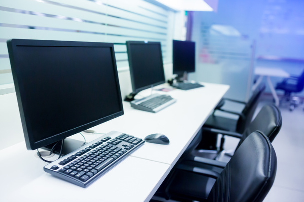composite image of computer in office or training room. the computer is on the table in a bright interior. white desk and black revolving chair with computer pc and mouse in office. - Photo, Image