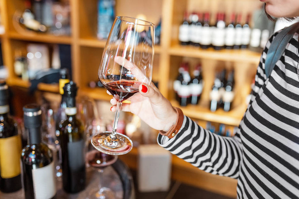 Mutlu asya Kadın koklama ve şaraphane dükkanında bir bardak kırmızı şarap tatma - Fotoğraf, Görsel