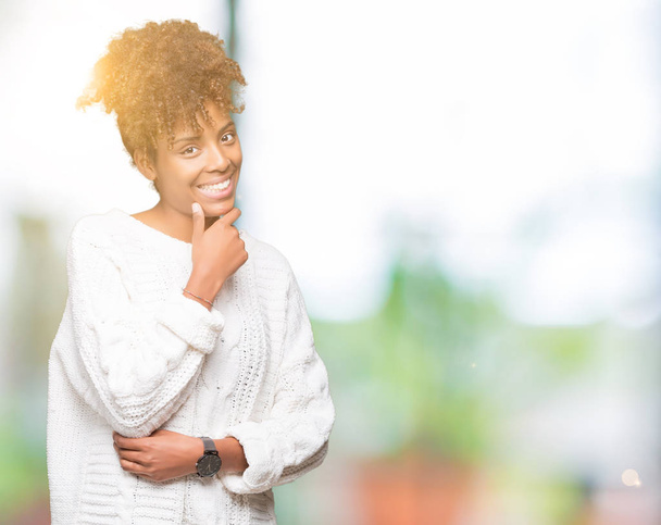 Beautiful young african american woman wearing winter sweater over isolated background looking confident at the camera with smile with crossed arms and hand raised on chin. Thinking positive. - Foto, afbeelding