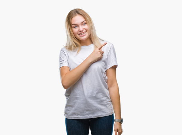 Young caucasian woman over isolated background cheerful with a smile of face pointing with hand and finger up to the side with happy and natural expression on face looking at the camera. - Foto, Imagen