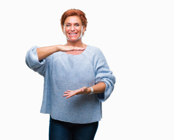 Attractief senior Kaukasische roodharige vrouw winter trui dragen over geïsoleerd achtergrond gebaren met de handen tonen grote en grote grootte teken, symbool van de maatregel. Glimlachend kijken naar de camera. Meten concept. - Foto, afbeelding