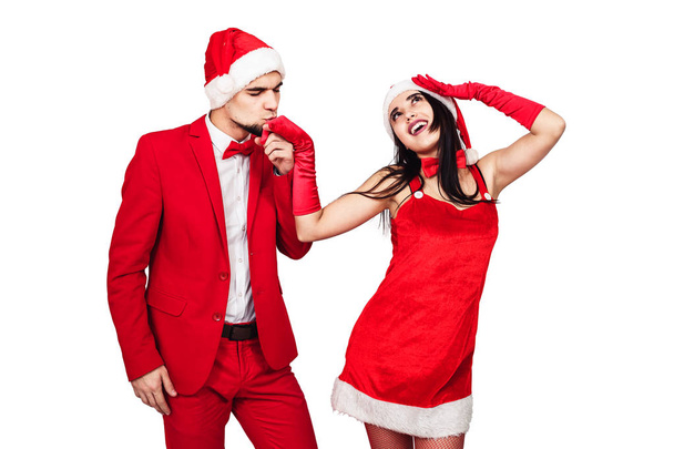mladý pár se baví na vánoční večírek. mladý muž a žena v červené šaty se Santa klobouky - Fotografie, Obrázek