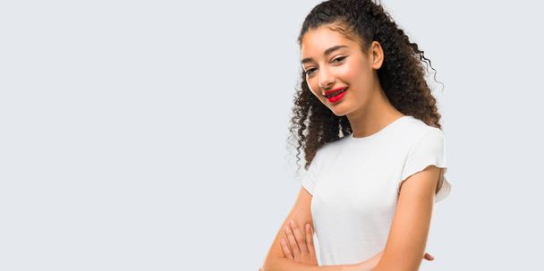 Young girl with curly hair keeping the arms crossed while smiling on grey background - Foto, Bild