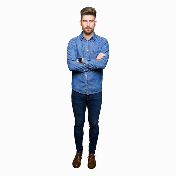 Young handsome blond man wearing casual denim shirt skeptic and nervous, disapproving expression on face with crossed arms. Negative person. - Fotoğraf, Görsel