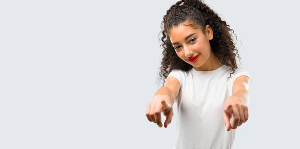 Young girl with curly hair points finger at you while smiling on grey background - Fotoğraf, Görsel