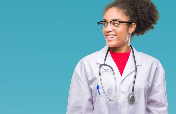 Молодая афро-американская врач женщина на изолированном фоне, глядя в сторону с улыбкой на лице, естественное выражение лица. Смеясь уверенно
. - Фото, изображение