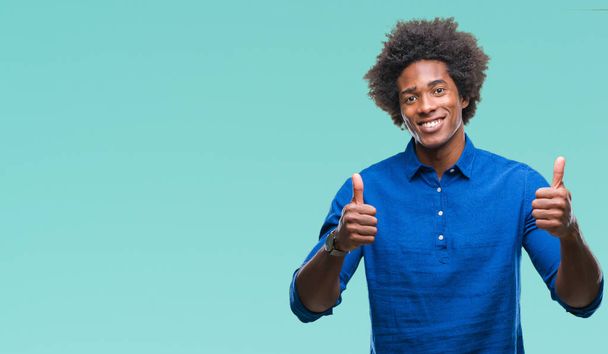 Afro american man over isolated background success sign doing positive gesture with hand, thumbs up smiling and happy. Looking at the camera with cheerful expression, winner gesture. - Foto, imagen