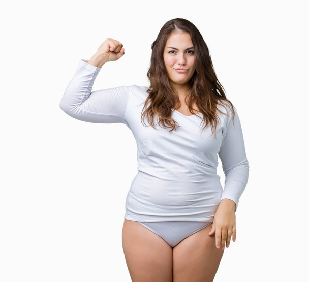 Beautiful plus size young overwight woman wearing white underwear over isolated background Strong person showing arm muscle, confident and proud of power - Foto, Imagen