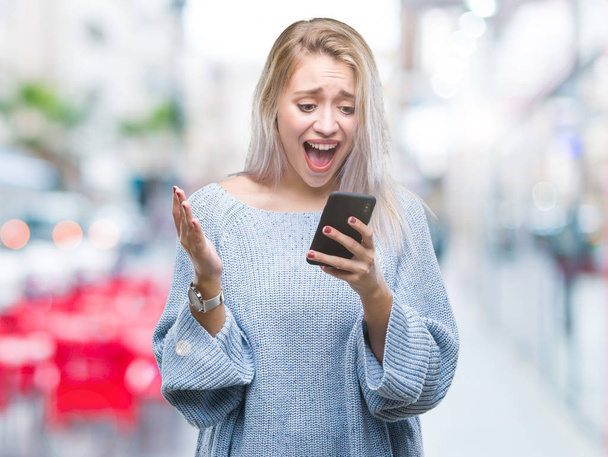 Jeune femme blonde envoyer un message par SMS en utilisant un smartphone sur fond isolé très heureux et excité, expression gagnante célébrant la victoire en criant avec un grand sourire et les mains levées
 - Photo, image