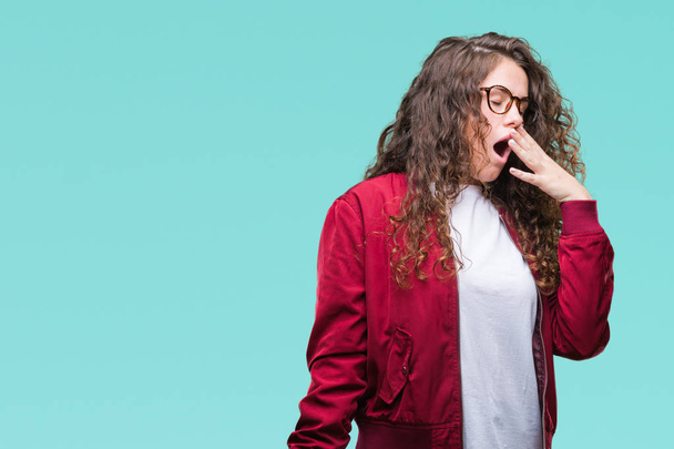 Beautiful brunette curly hair young girl wearing jacket and glasses over isolated background bored yawning tired covering mouth with hand. Restless and sleepiness. - Fotografie, Obrázek