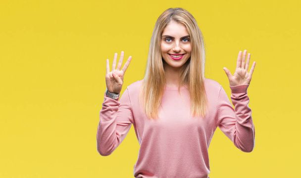 Молода красива блондинка носить рожевий зимовий светр над ізольованим тлом, показуючи і вказуючи пальцями номер дев'ять, посміхаючись впевнено і щасливо
. - Фото, зображення